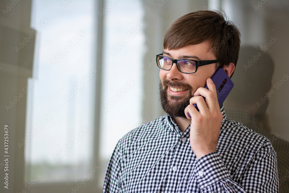 Close-up portrait of a young man who speaks on the phone positive and smiles Close-up portrait of a young man who speaks on the phone positive and smiles