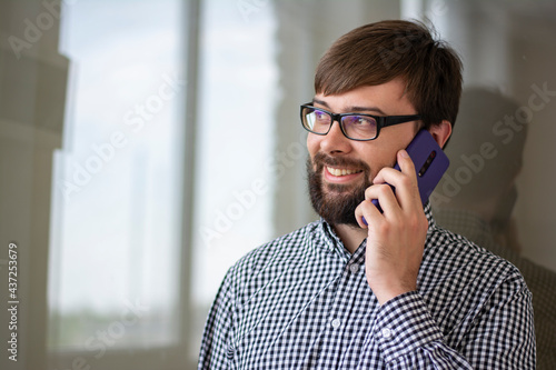 Close-up portrait of a young man who speaks on the phone positive and smiles