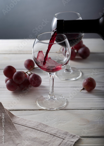 Two glasses of red wine on white wooden table. Still life composition with space for text.