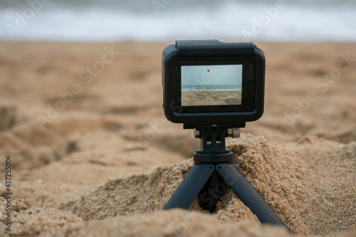 Compact action camera capturing beach scene, isolated over the outside background photo