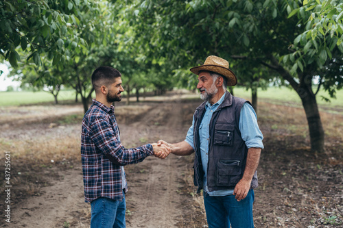ranchers handshake in walnut orchard © cherryandbees