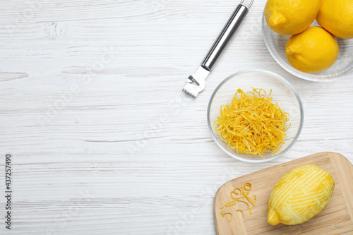 Flat lay composition with fresh lemon zest on white wooden table. Space for text