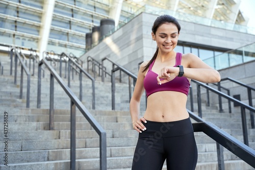 Happy athletic lady looking on smartwatch outdoor © Friends Stock