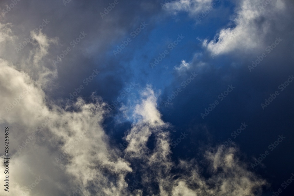 White thunderclouds in the clear blue sky. Heavenly landscape after a thunderstorm. Bright colorful thunder clouds in the sun light. Picturesque clouds in the evening light. Abstract bright skyscape.