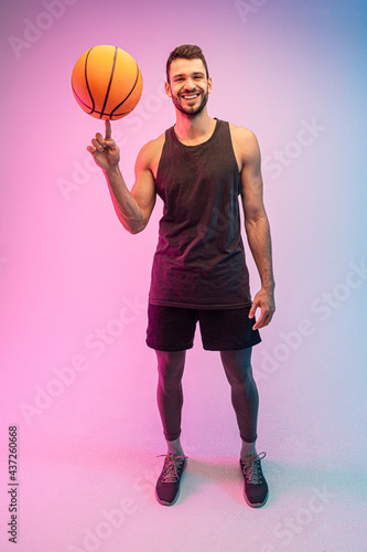 Young sportsman spinning basketball ball on finger