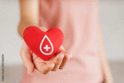 Woman hands holding red heart with blood donor sign. healthcare, medicine and blood donation concept. photo