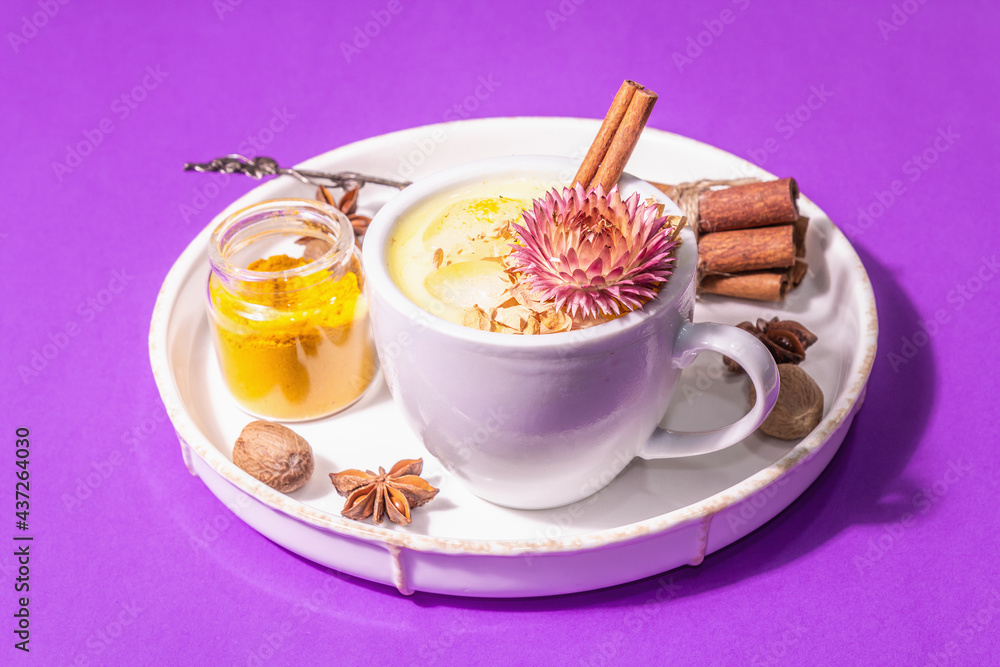 Golden turmeric milk with ice on bright yellow background Golden turmeric milk with ice on bright yellow background