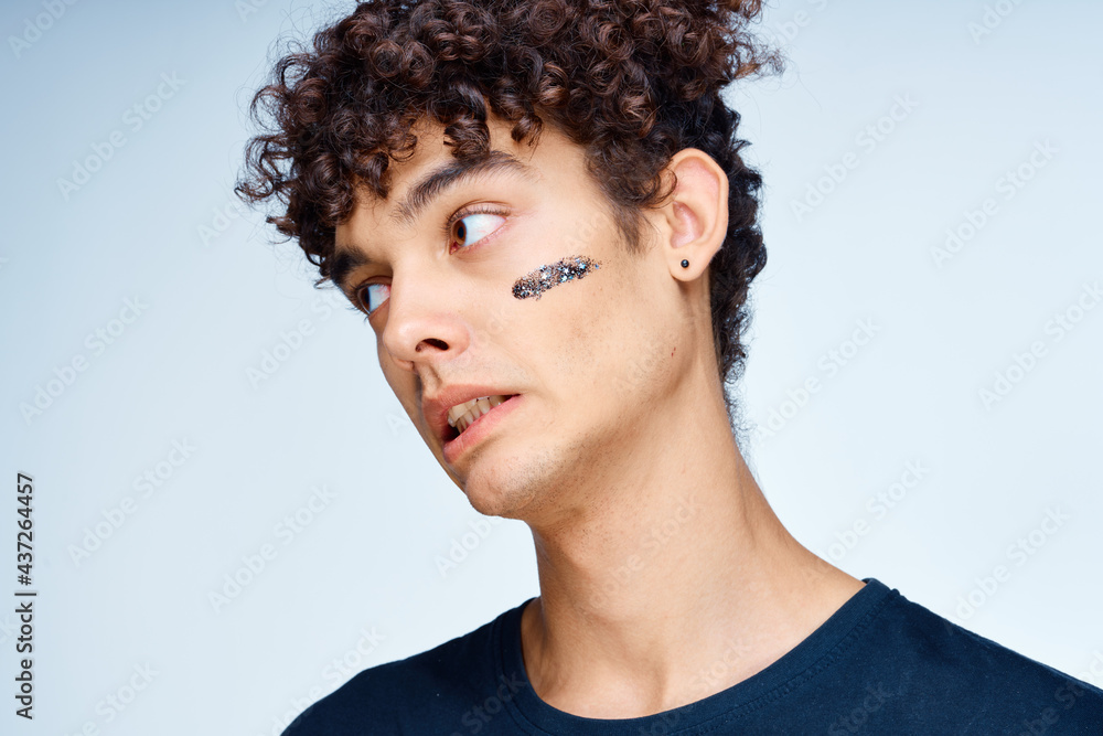 curly-haired guy in a black t-shirt cosmetics on the face clean skin curly-haired guy in a black t-shirt cosmetics on the face clean skin