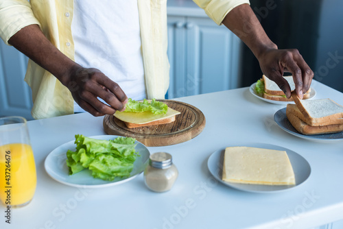 cropped view of african american man preparing sandwiches in kitchen