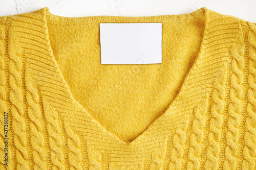 Closeup of an inner label on the neck of a pretty yellow wool sweater. Blank space to place a logo, text or image