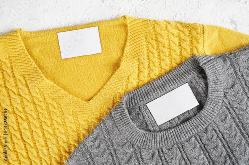 Mockup of an inner label on the necks of a pretty gray and yellow wool sweaters. Blank spaces to place a logo, text or image