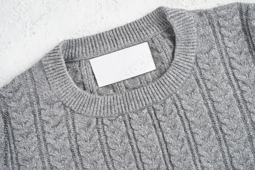 Mockup of an inner label on the neck of a pretty gray wool sweater. Blank space to place a logo, text or image