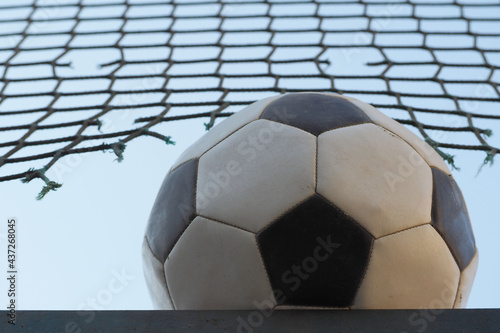 round soccer ball in black and white on grid and sky background bottom view