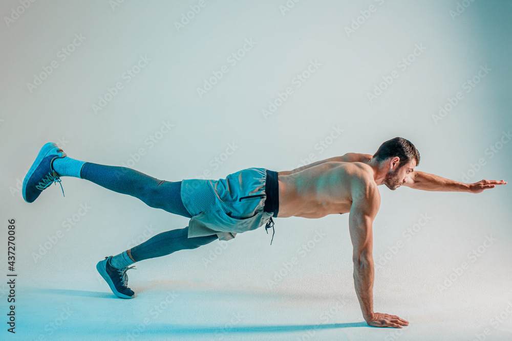 Young european sportsman doing plank in studio Young european sportsman doing plank in studio