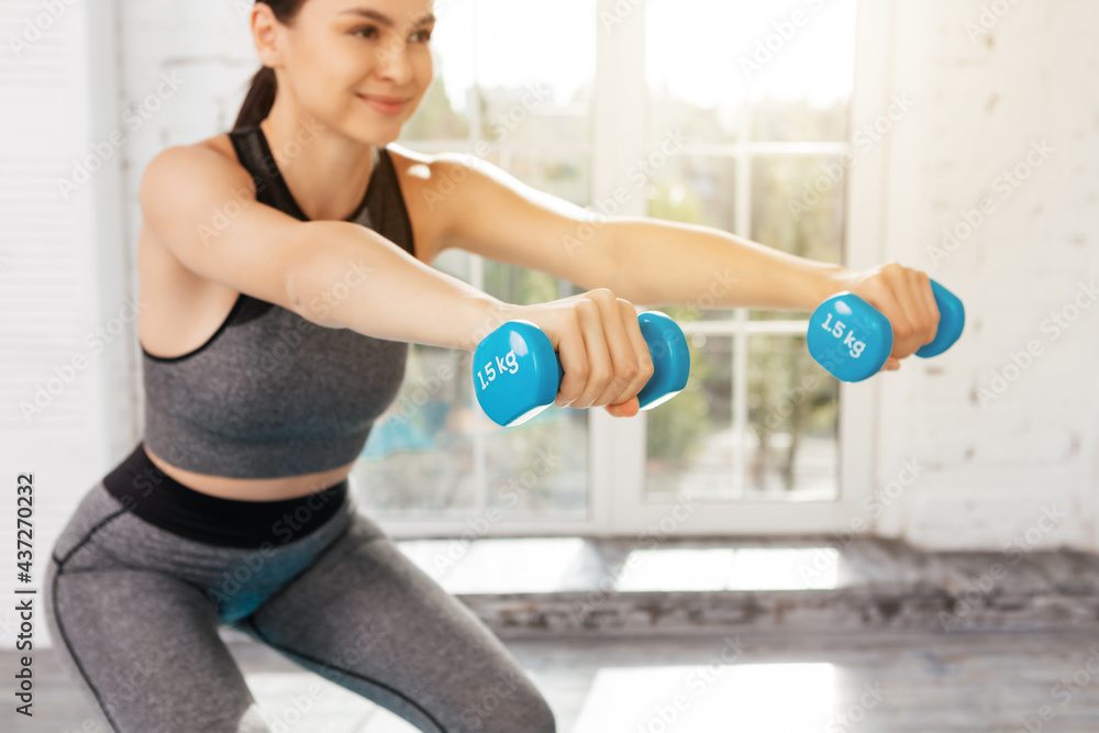 Charming female exercising with a pair of dumbbells