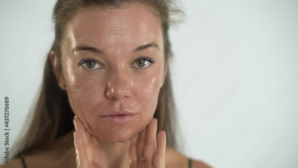 A young beautiful girl applies cream to her face. A young beautiful girl applies cream to her face.