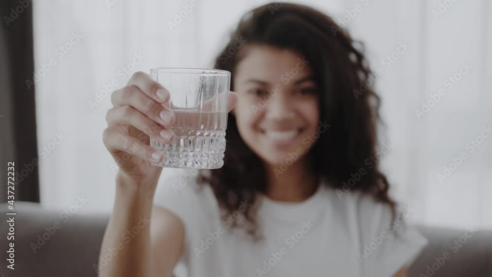 smiling young african woman holding glass of fresh clear purified potable water offer to drink. Happy healthy black female look at camera propose you to enjoy clean sparkling aqua smiling young african woman holding glass of fresh clear purified potable water offer to drink. Happy healthy black female look at camera propose you to enjoy clean sparkling aqua
