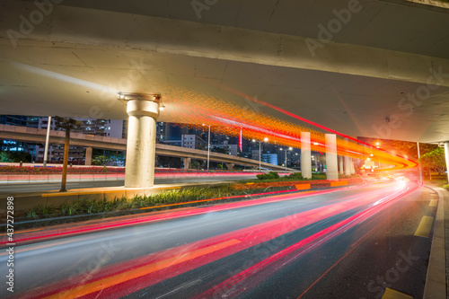 Overpass and red light trails at night on the illuminated highway © xiaoliangge
