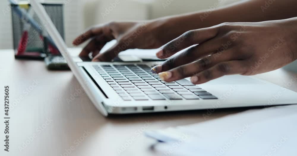 Hands of woman checking mobile phone while typing on laptop at home Hands of woman checking mobile phone while typing on laptop at home