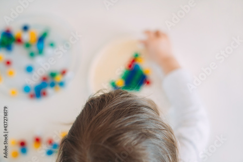 Child playing mosaic on table at home with blur