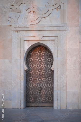 elegant ornamental forged metal  entrance to a beautiful Islamic mosque on the ocean at sunset © Alevtina
