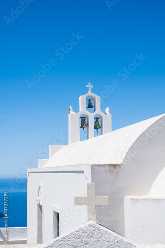 White bell tower of the traditional Greek Orthodox church on the island of Santorini. Blue sky on background.