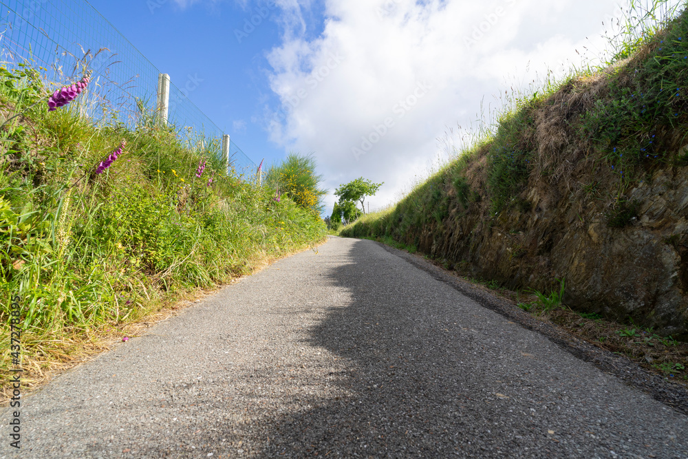 Sloping road with shade and sun in a rural area with a blue sky full of clouds. Outdoor exercise concept.