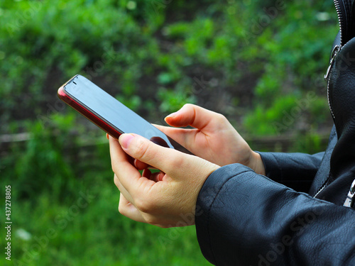 the girls are holding the phone in their hands. Side view shot of woman's hands using smart phone in nature, online shopping concept.