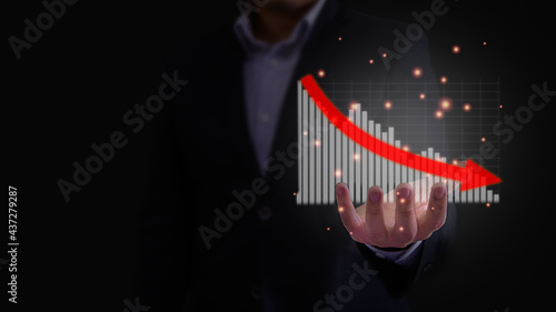 Business downturn, decline, loss, failure concept. Businessman is showing hologram financial stok investment report graph in bar chart on his hand with red arrow point down in dark background.