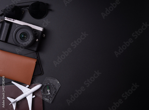 Travel concept:Top view photo of sunglasses compass camera and plane model on passport cover on dark background