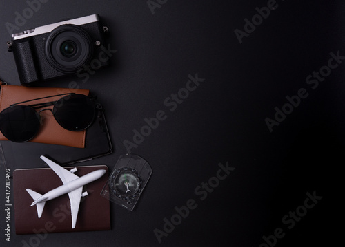 Travel concept:Top view photo of sunglasses compass camera and plane model on passport cover on dark background
