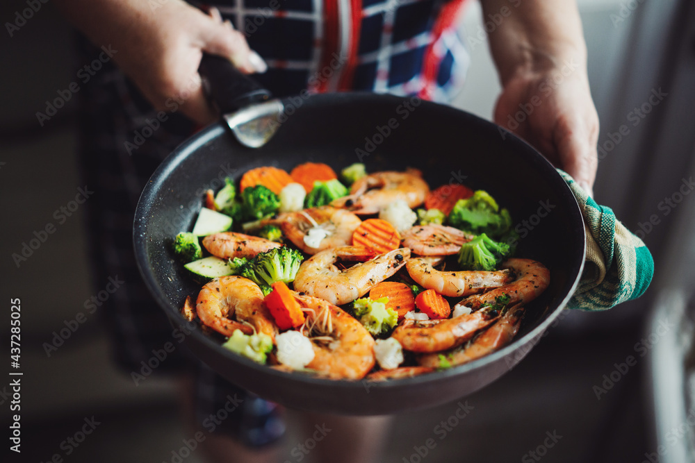 Woman cooking vegetables and shrimps on pan Woman cooking vegetables and shrimps on pan