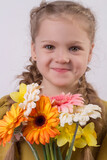 beautiful smiling blonde girl with pigtails with gerberas in her hands