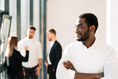 Black male executive and his employees in the background. Office worker portrait