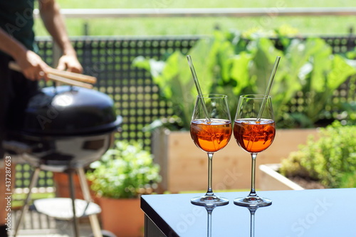two summer apperitive drinks with a terrace barbecue in the background photo