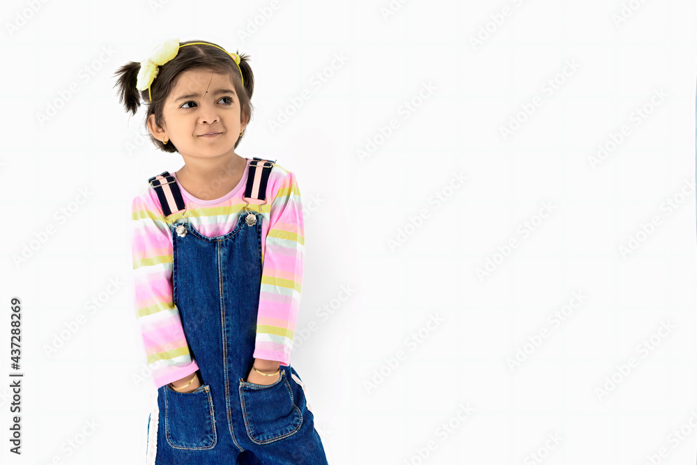 Laughing cute girl portrait with denim cloths and pony tail at Studio with blank space at right. Little child smiling and looking away up with white background studio shot Laughing cute girl portrait with denim cloths and pony tail at Studio with blank space at right. Little child smiling and looking away up with white background studio shot