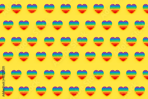 Pattern. Colorful trendy Pop it heart shape fidgets toy for kids on a yellow background.
