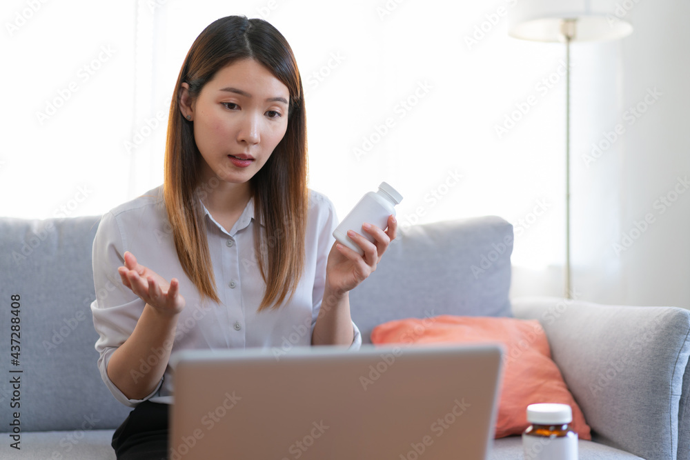 Asian female medical assistant making video call with patients for online support, Woman explaining medicine bottles working from home while coronavirus pandemic Asian female medical assistant making video call with patients for online support, Woman explaining medicine bottles working from home while coronavirus pandemic