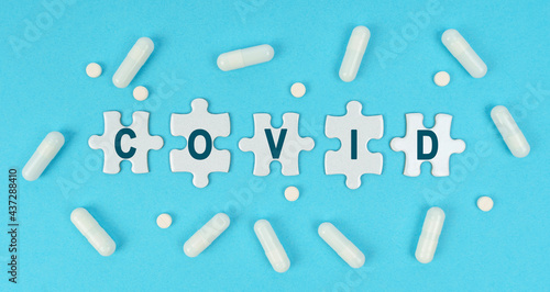 On a blue background, there are pills and puzzles with the inscription - COVID