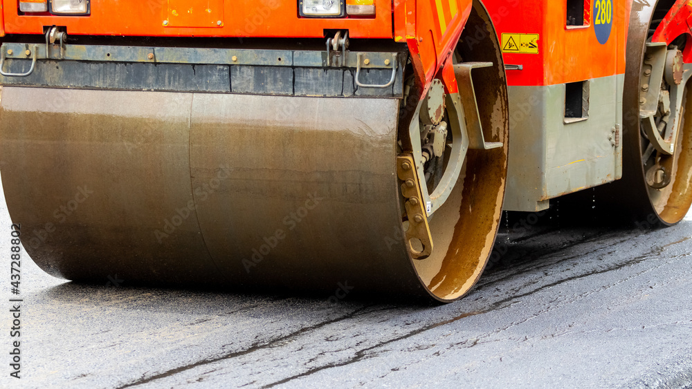 Asphalt paver on the road during asphalt compaction close up. Road repair. Laying a new road Asphalt paver on the road during asphalt compaction close up. Road repair. Laying a new road