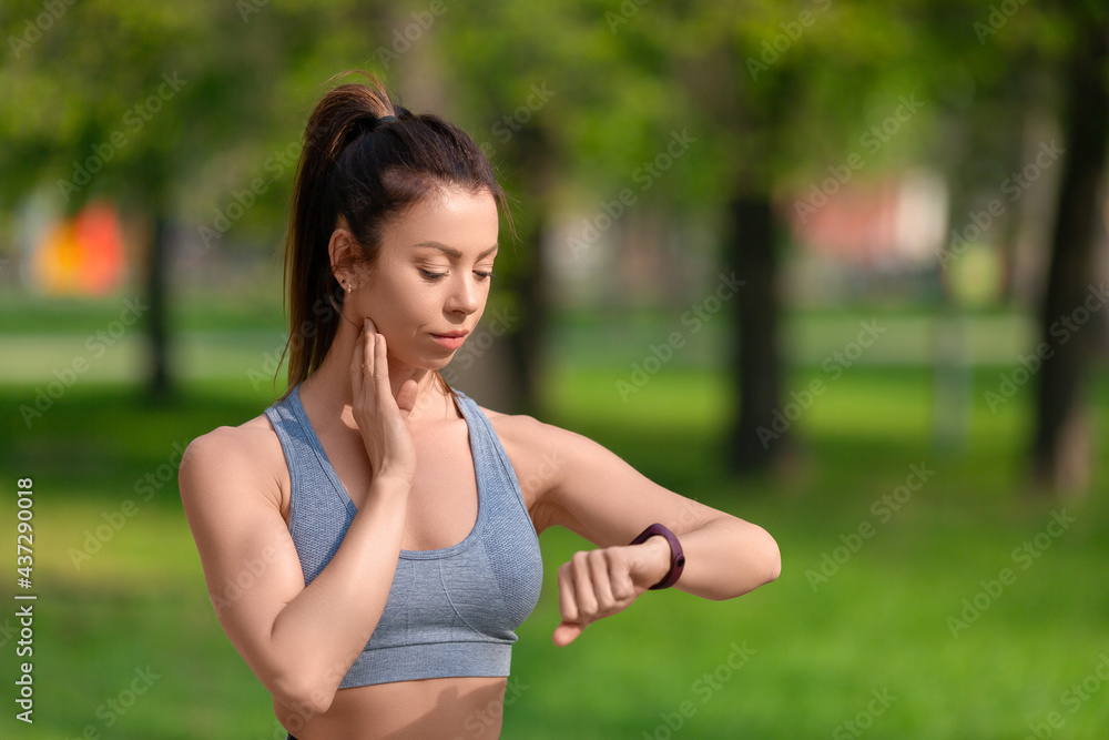 Healthy lifestyle concept - woman checks her pulse after jogging workout in the park. Healthy lifestyle concept - woman checks her pulse after jogging workout in the park.