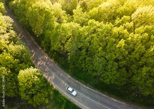 White Car on Highway road in summer time nature from air in the forest. View from a drone. Aerial view.