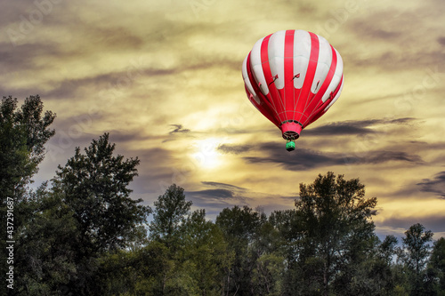 A beautiful sunrise over the forest with a hot air balloon in the sky in the early morning.