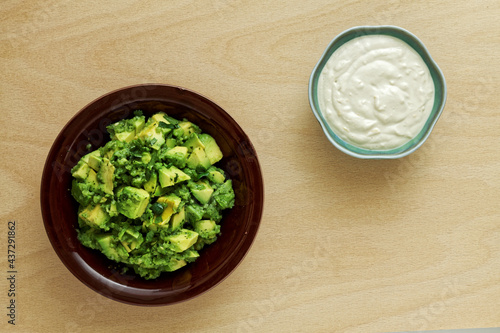 Bowls with fresh guacamole avocado mash and tahini with yoghurt dressing sauce. Flat lay, top view.