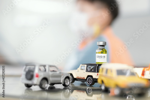 Coronavirus COVID-19 vaccine vials on car toy model with blurry child as background.Concept background for new corona virus (novel Coronavirus 2019 disease,COVID-19 vaccine for children.