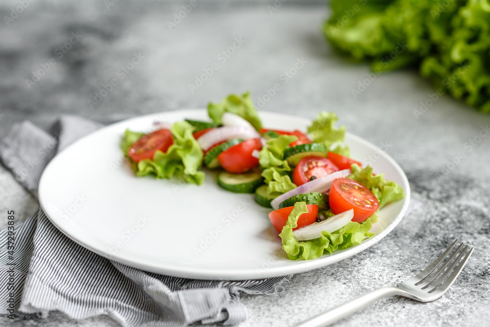 Fresh delicious salad with vegetables: tomato, cucumber, onions and greens with olive oil