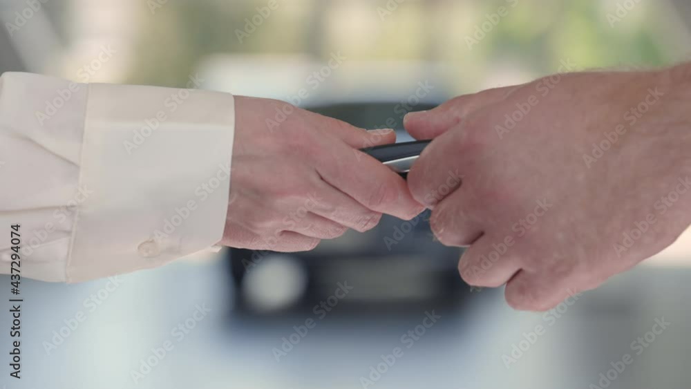 Female seller presenting keys from new car to male client Female seller presenting keys from new car to male client