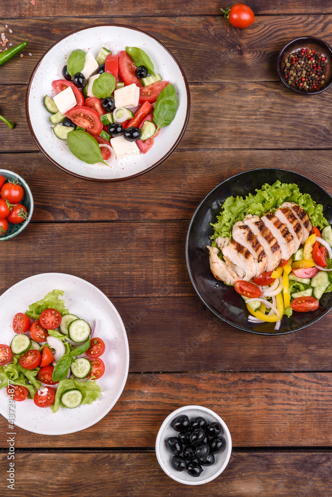 Three fresh delicious salads with chicken, tomato, cucumber, onions and greens with olive oil