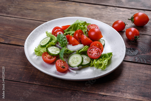 Fresh delicious salad with vegetables: tomato, cucumber, onions and greens with olive oil