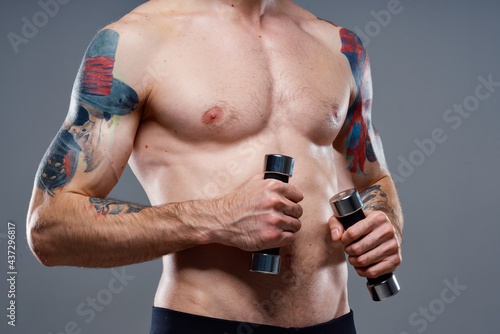 male athlete with a tattoo on his arm naked torso inflated muscles dumbbells fitness